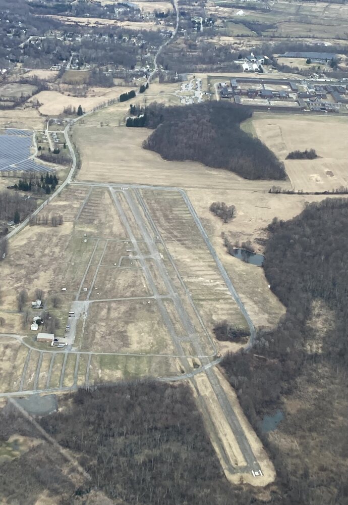 Aerial view of a small airport with a runway and hangars