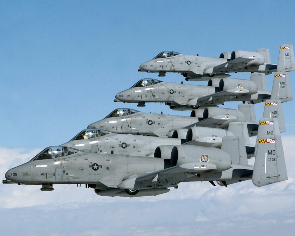 Gray A-10 jets in formation above the clouds