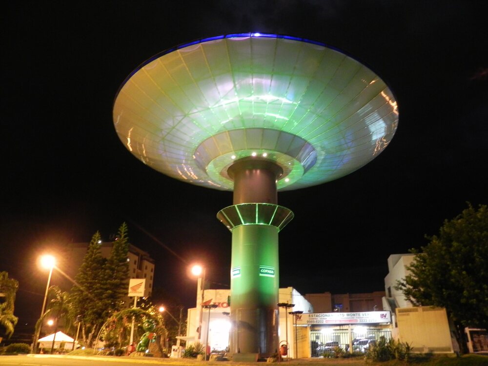 Flying-saucer-shaped water tower lit up at night in a town square