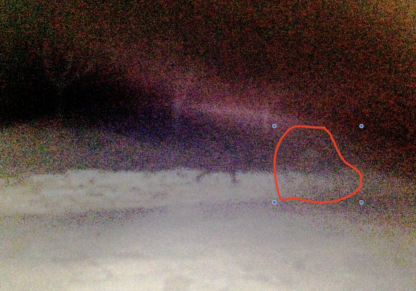 The contrast photo with a red outline drawn by hand over the area on the right, just above the wall